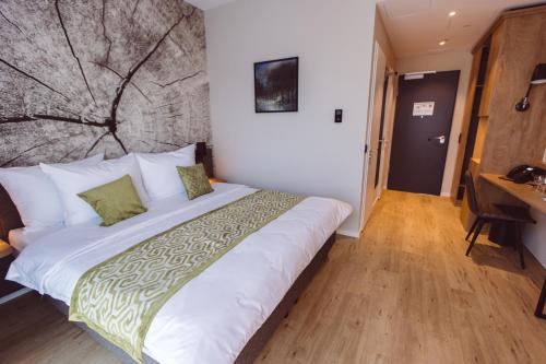 a bedroom with a large white bed and a desk at Hotel Libertas elements pure in Freiburg im Breisgau