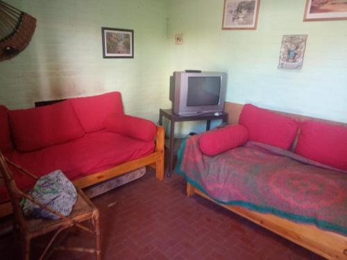 sala de estar con 2 sofás rojos y TV en Duplex 4 personas en Villa Gesell