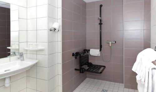 a bathroom with a shower with pink and white tiles at Hôtel Sainte Suzanne in Lourdes