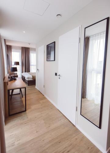 a living room with a large mirror and a bedroom at Hotel Libertas elements pure in Freiburg im Breisgau