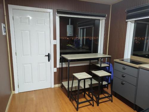 a kitchen with a counter and a table and a door at atenea in Punta Arenas