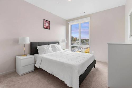 - une chambre blanche avec un grand lit et une fenêtre dans l'établissement Luxurious&modern with balcony on the charles River, à Boston