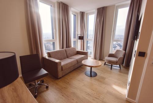 a living room with a couch and chairs and windows at Hotel Libertas elements pure in Freiburg im Breisgau