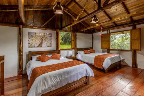 two beds in a room with wooden ceilings and windows at Ecohotel Piedemonte in Salento