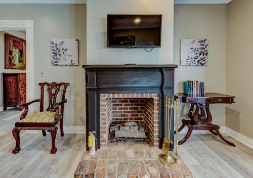 ein Wohnzimmer mit einem Kamin, einem Stuhl und einem TV in der Unterkunft The Inn at Cedar Grove in Vicksburg