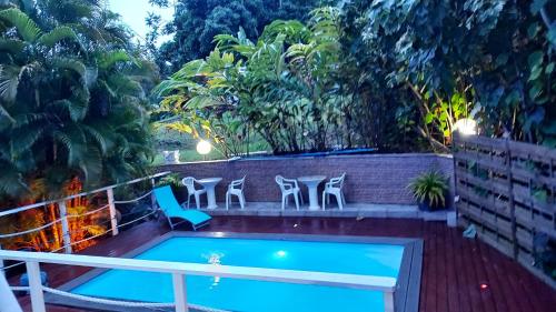 a balcony with a pool and chairs and trees at Appartement charmant à Rivière-Pilote avec piscine partagéeB in Rivière-Pilote