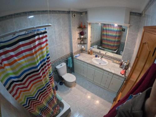 a bathroom with a rainbow shower curtain and a sink at Comparte Espacio en Chiclana in Chiclana de la Frontera