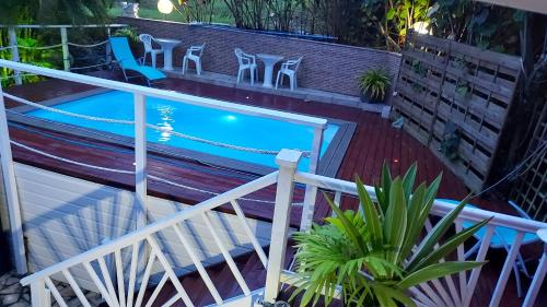 a swimming pool on a balcony with chairs and plants at Appartement charmant à Rivière-Pilote avec piscine partagéeB in Rivière-Pilote