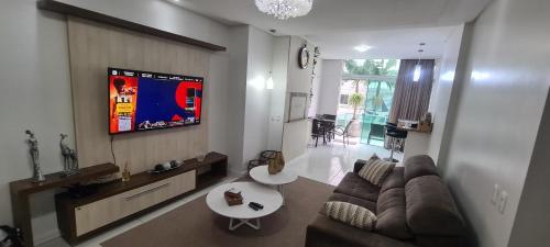 a living room with a couch and a tv on a wall at Excelente Apartamento Alto Padrão Centro Ed Dubai in Capão da Canoa