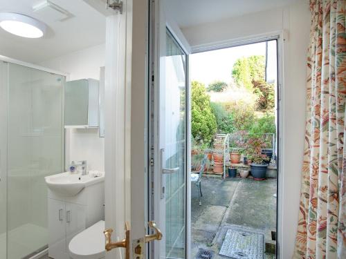 a bathroom with a sink and a glass shower door at Waterside Park Annexe in Kingsbridge