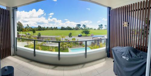 a room with a large window with a view of a golf course at Tahuna Beach Apartment in Nelson