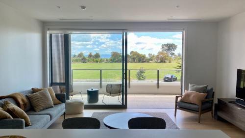 a living room with a couch and a large window at Tahuna Beach Apartment in Nelson