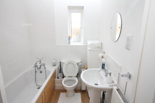 Baño blanco con aseo y lavamanos en Elegant Guest House, en Spinney Hill