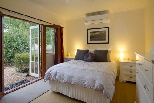 Apple Tree FlatにあるRiverlea Cottageのベッドルーム1室(ベッド1台付)、スライド式ガラスドアが備わります。