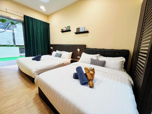 two beds with a teddy bear sitting on top of them at Maison life 小居屋 The Loft Imago in Kota Kinabalu
