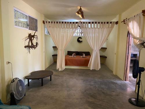 a bedroom with a bed with curtains and a table at Casa Tonantzin in Zipolite