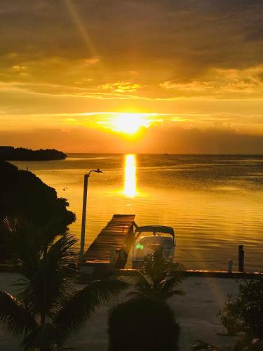 a boat in the water with a sunset in the background at Hidden Treasure Vacation Home BayBlue Suite 1 in Belize City