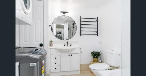 a white bathroom with a sink and a mirror at Pacific Place Apartments in Gold Coast