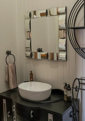 a bathroom with a sink and a mirror on a counter at Ruapehu's 5-Star OLD POST OFFICE - 1-4 Bdr West Wing in Owhango