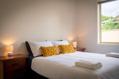 um quarto com uma grande cama branca com almofadas amarelas em Blayney Retreat-Central & Comfortable em Blayney