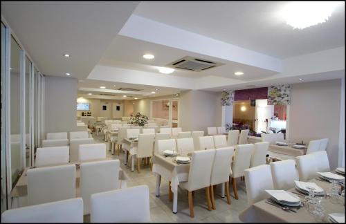 una sala da pranzo con tavoli bianchi e sedie bianche di Hôtel Peyramale a Lourdes