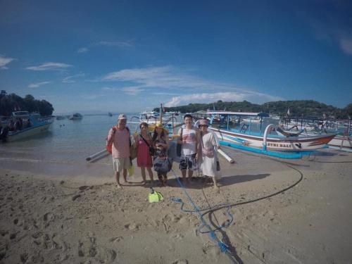 a group of people standing on a beach with boats at SNORKELING AT PADANGBAI BY KAI TRIP TOMORROW in Padangbai