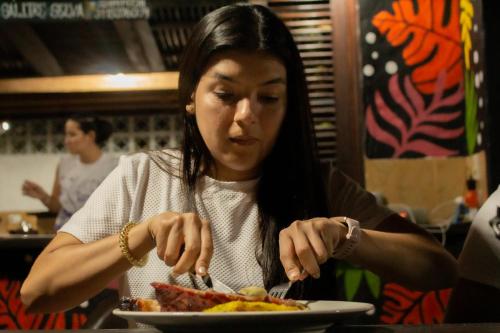 Hotel Bahía Aguacate في كابورغانا: امرأة تجلس على طاولة تأكل طبق من الطعام