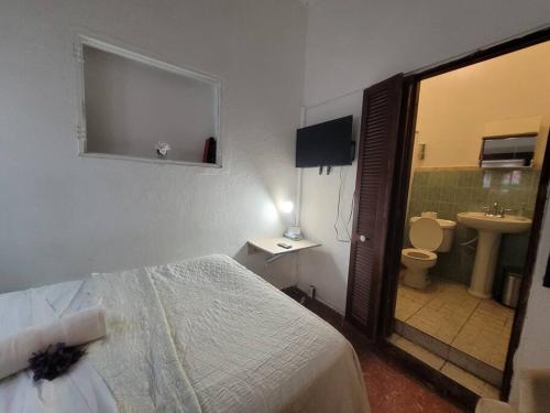 ein Schlafzimmer mit einem Bett und ein Badezimmer mit einem Waschbecken in der Unterkunft fabulous rooftop 2 colonial room for 4 in Santo Domingo