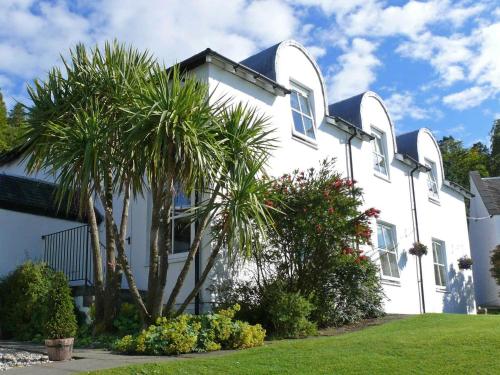 a white house with palm trees in front of it at The Pierhouse Hotel in Port Appin