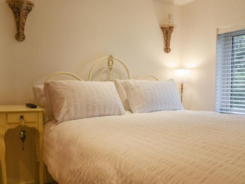 1 dormitorio con 1 cama con sábanas blancas y ventana en Pippin Cottage en Bures Saint Mary