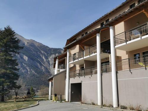 un grand bâtiment avec une montagne en arrière-plan dans l'établissement Studio confortable à Jausiers avec terrasse et accès piscine, idéal pour 4 personnes - FR-1-165B-56, à Jausiers