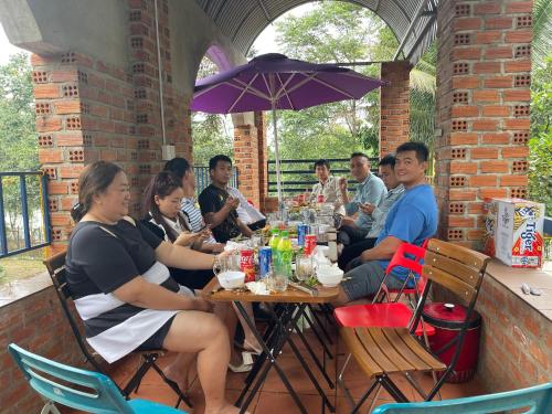 a group of people sitting at a table with an umbrella at family garden 