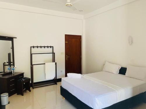 a bedroom with a bed and a dresser and a mirror at The Kingslayer Resort in Negombo