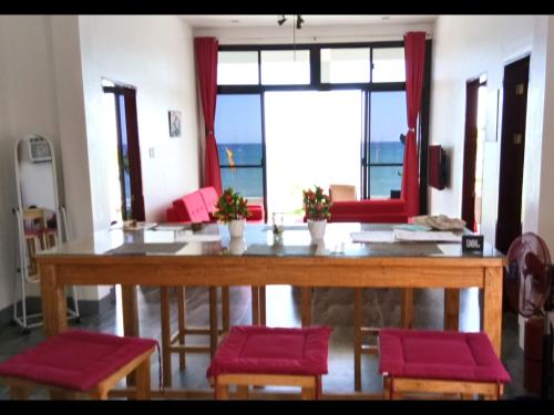 Dimiao的住宿－BambooBeachVilla2 AC NEW OCEANFRONT POOL sunsetview garden kitchen SATELLITE STARLINK WI-FI，一张带红色椅子的餐桌和大窗户