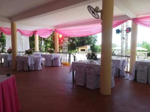 a banquet hall with white tables and pink tents at Happy Sunset's Inn in Larena