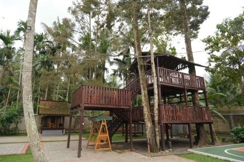 una casa en un árbol en un parque con parque infantil en Kayon Griya Osing Villa - Ijen en Licin