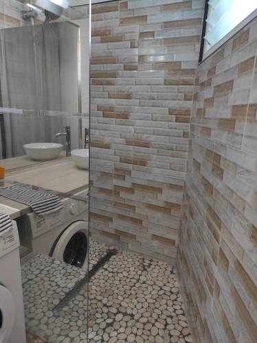 a bathroom with a washing machine and a stone wall at Studio le Sucrier in Saint-François