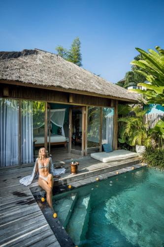 a woman sitting on a deck next to a swimming pool at Villa Markisa Echo Beach in Canggu