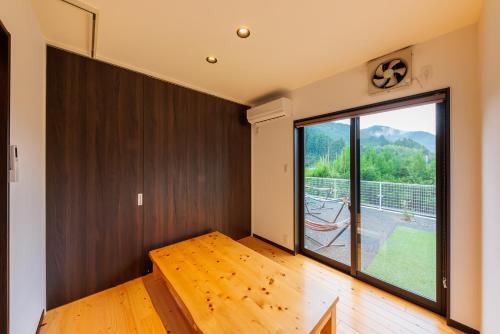 a room with a wooden floor and a large window at 日本の秘境で味わう絶品地鶏 ジローのおうち in Aki