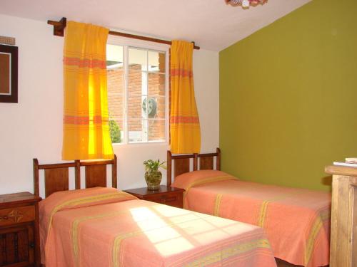 2 camas en una habitación con paredes amarillas y verdes en Los Ócalos Villas, en Huasca de Ocampo