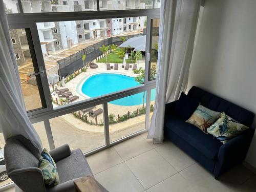 a living room with a view of a pool through a window at Armonia De Las Terrenas Gorgeous Penthouse in Las Terrenas