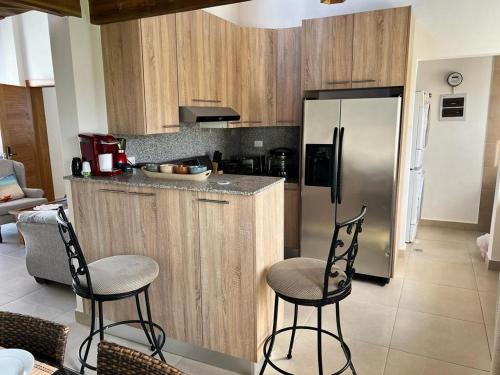 a kitchen with a stainless steel refrigerator and two chairs at Armonia De Las Terrenas Gorgeous Penthouse in Las Terrenas