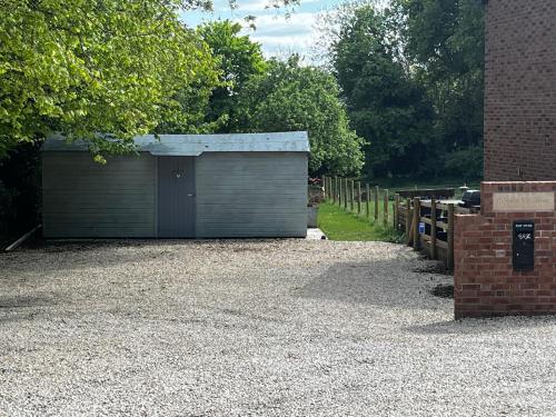 a garage in a gravel driveway next to a brick building at Pear Tree Cottage Courtyard in Shrewsbury