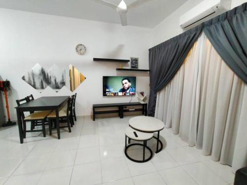 ein Wohnzimmer mit einem Tisch und einem TV. in der Unterkunft SS CondoStay Residensi Lili, Nilai nearby KLIA, USIM - infinity pool, wifi, smart tv in Nilai