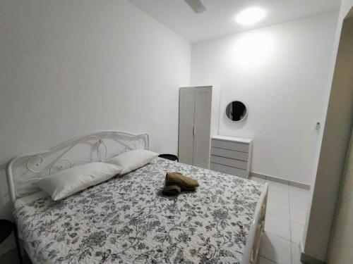 a white bedroom with a bed with a flowery bedspread and a hat at SS CondoStay Residensi Lili, Nilai nearby KLIA, USIM - infinity pool, wifi, smart tv in Nilai