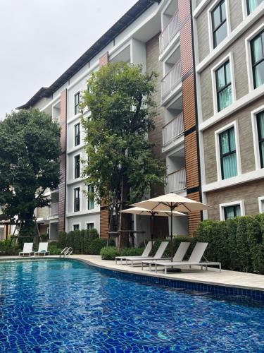 a swimming pool with chairs and an umbrella next to a building at Seaside vacation in Rawai Beach