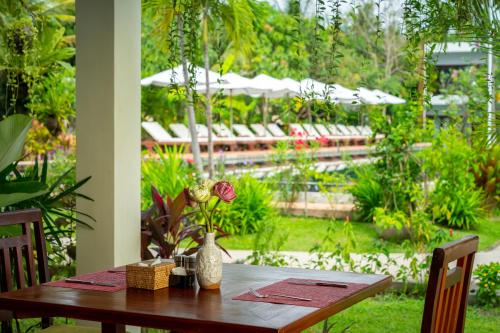a wooden table with a vase of flowers on it at Khmer House Resort in Siem Reap