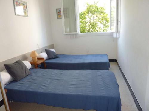 une chambre avec deux lits et une fenêtre dans l'établissement Appartement 6 pers, terrasse, parking, centre Marseillan Plage - FR-1-387-158, à Marseillan