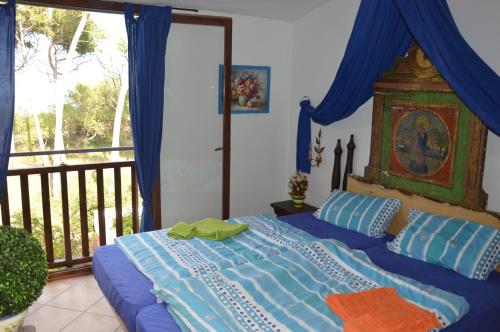 a bedroom with a bed with a blue comforter and a balcony at Beach House Casa Erica in Ampurias