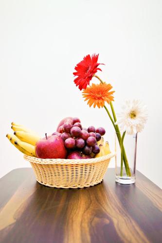 a basket of fruit and a vase with a flower at Villa Grand Hotel Near Kempegowda International Airport in Bengaluru